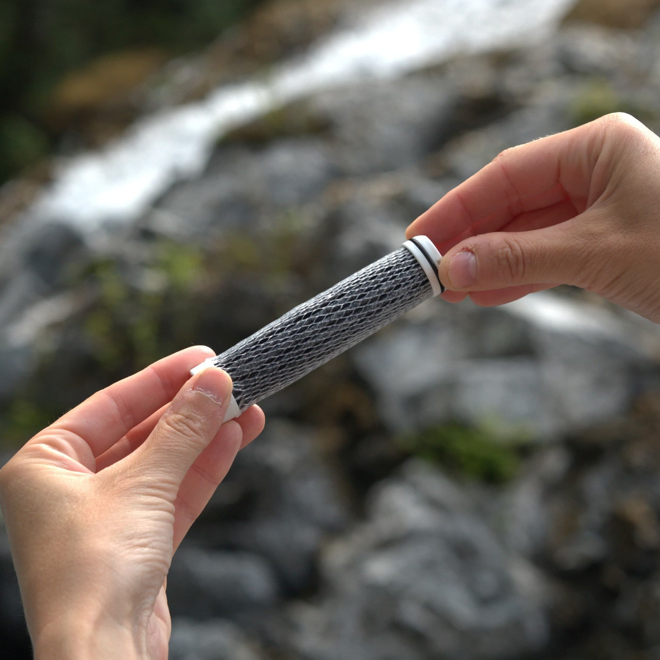 A close up of the AtomX Cartridge for the NOMAD SafeSip, giving access to clean and sustainable water anywhere you go. The cartridge hold by the hand purifies all waterbone contaminants