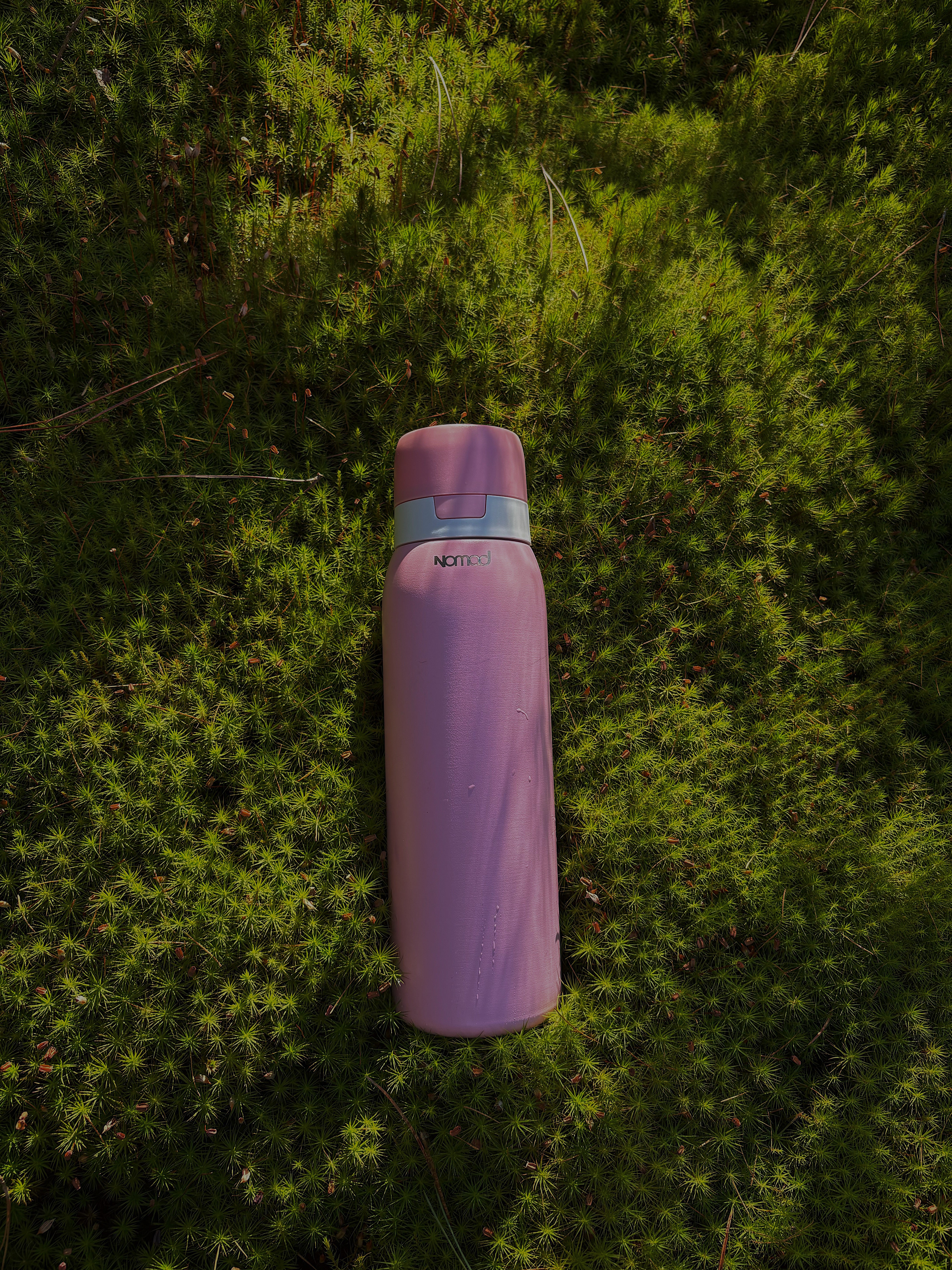 NOMAD filtered water bottle on wooden surface showing AtomX™ filtration system for clean, safe hydration, ideal for outdoor adventures and everyday use.