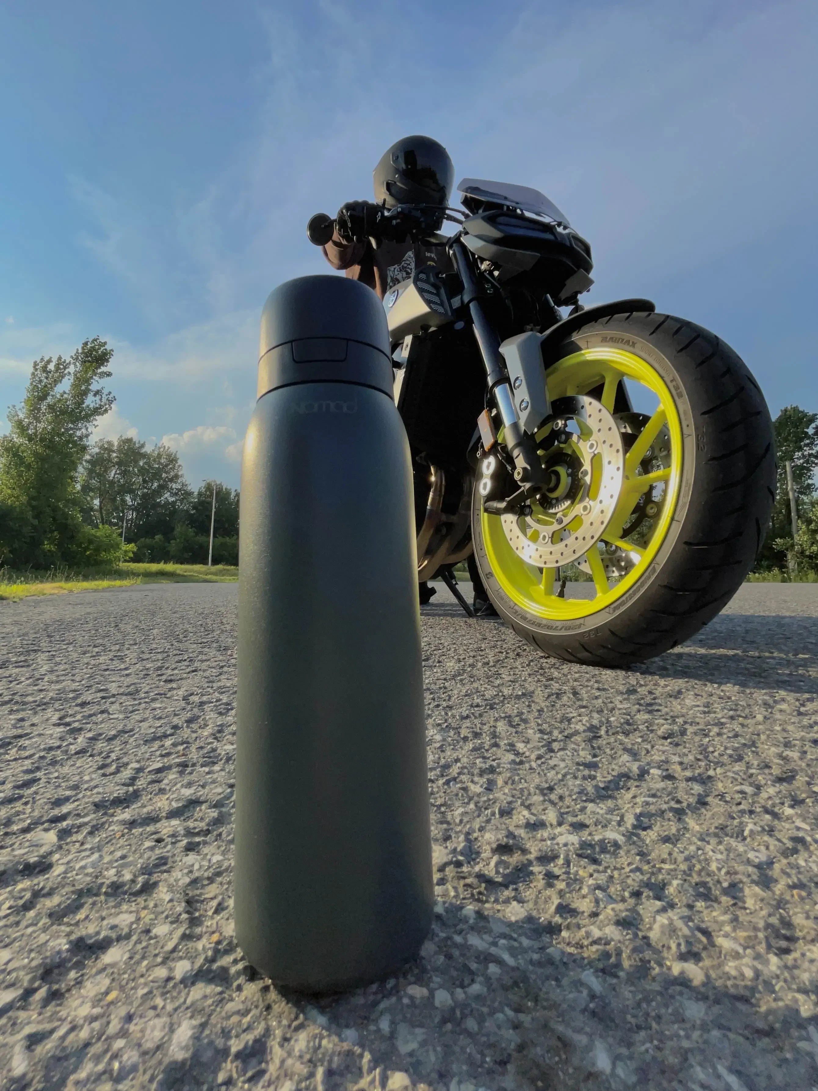 Black water bottle SafeSip on the ground, next to a motorcycle