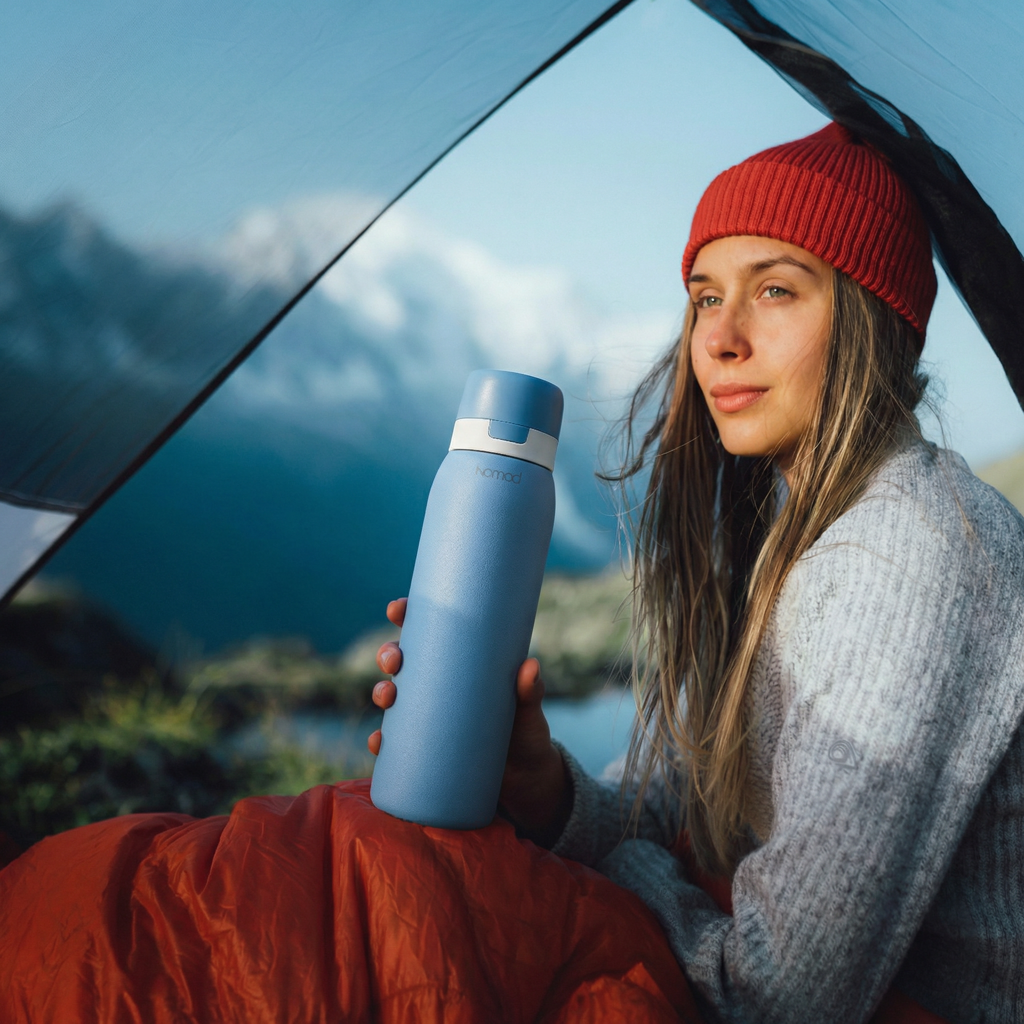 Woman holding a blue safesip water bottle with a scenic background