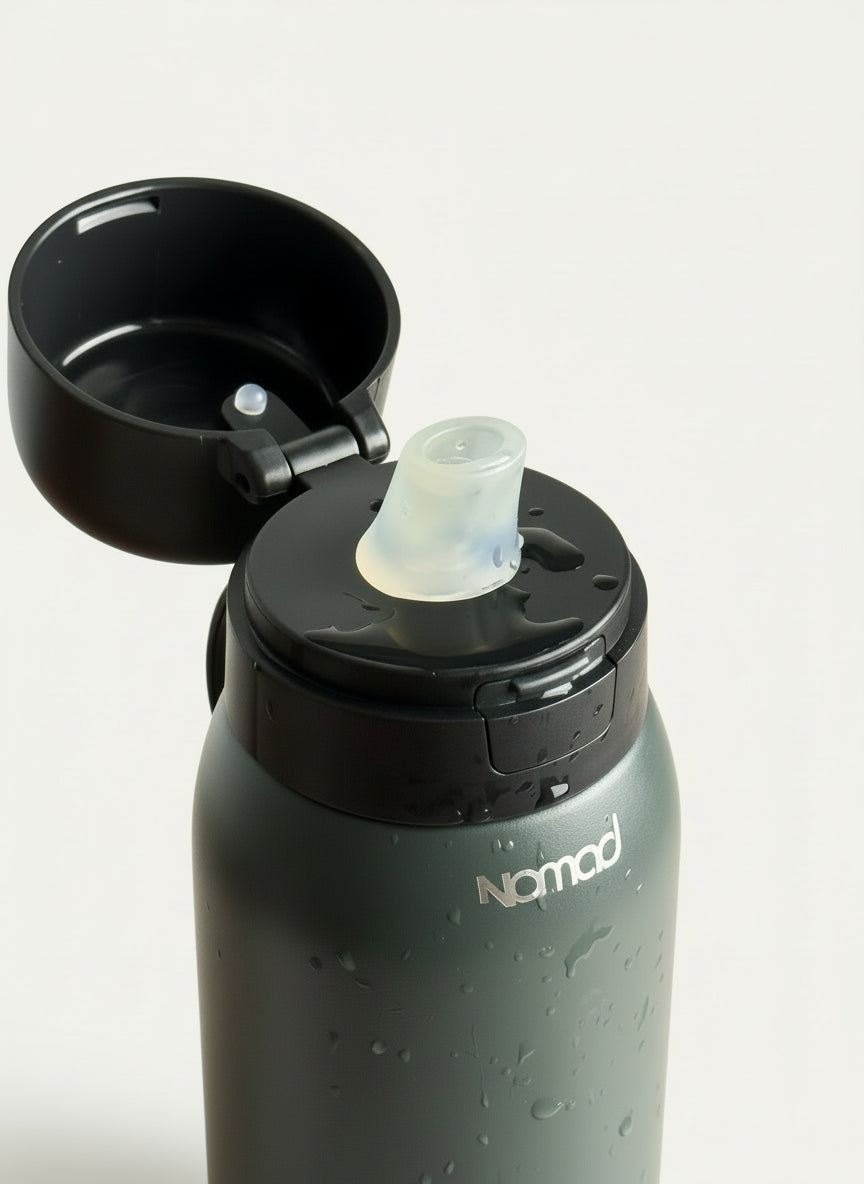 Black NOMAD filtered water bottle with a black cap on a wooden surface