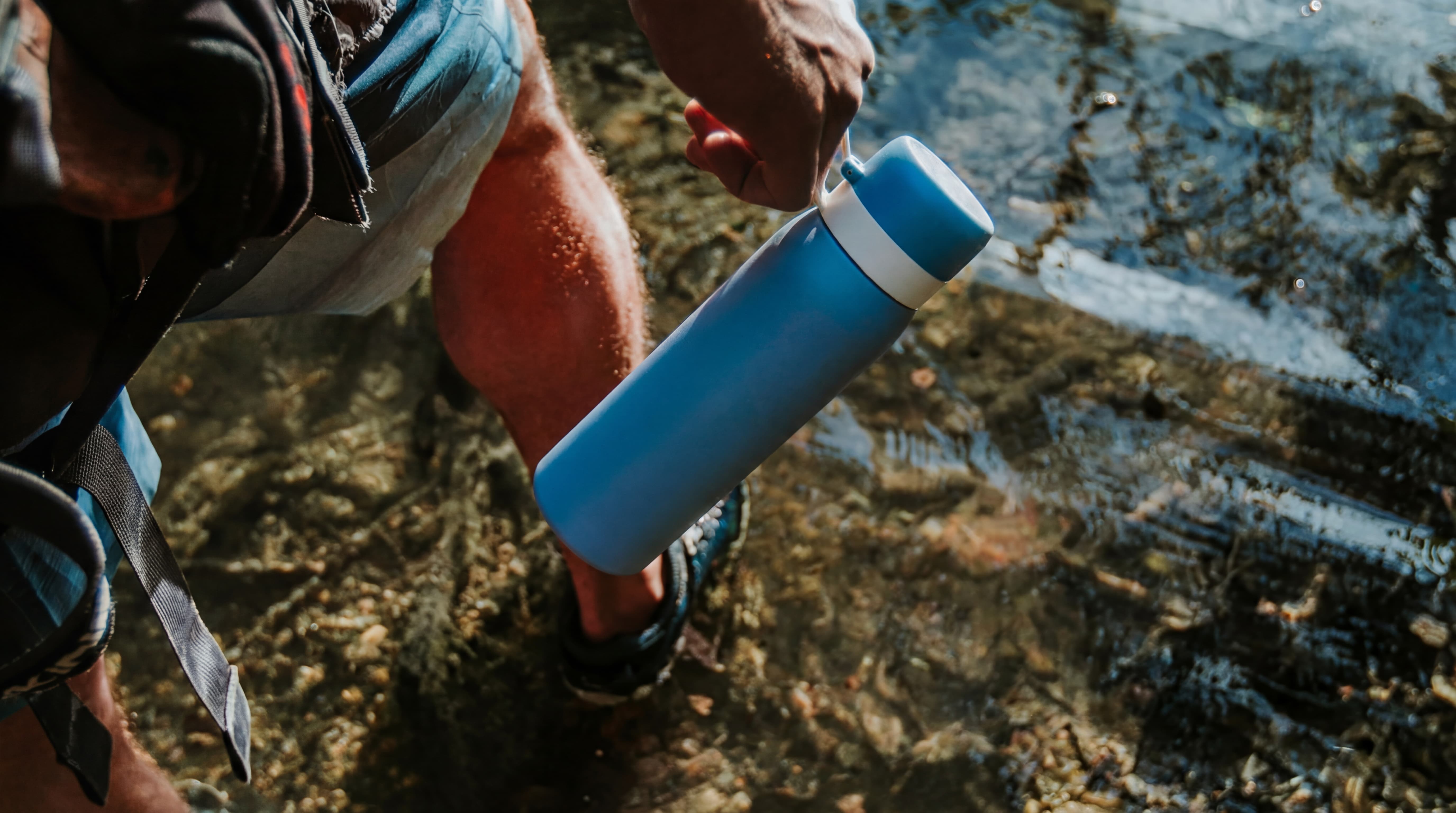 NOMAD Purifier bottle hold by a man walking in the woods.