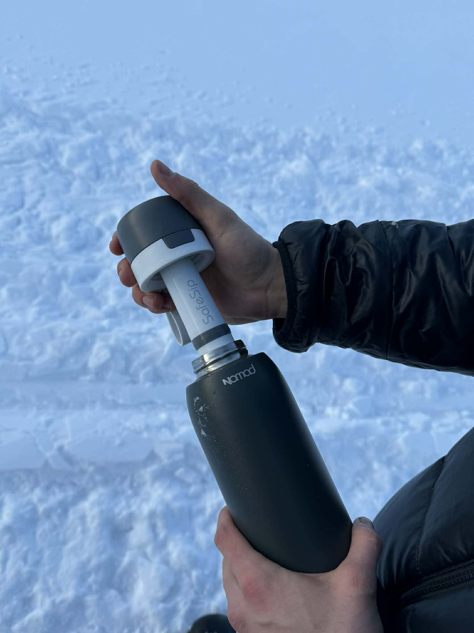 picture of a man holding and opening a bottle with "nomad" branding on it for cleaner water on the go.