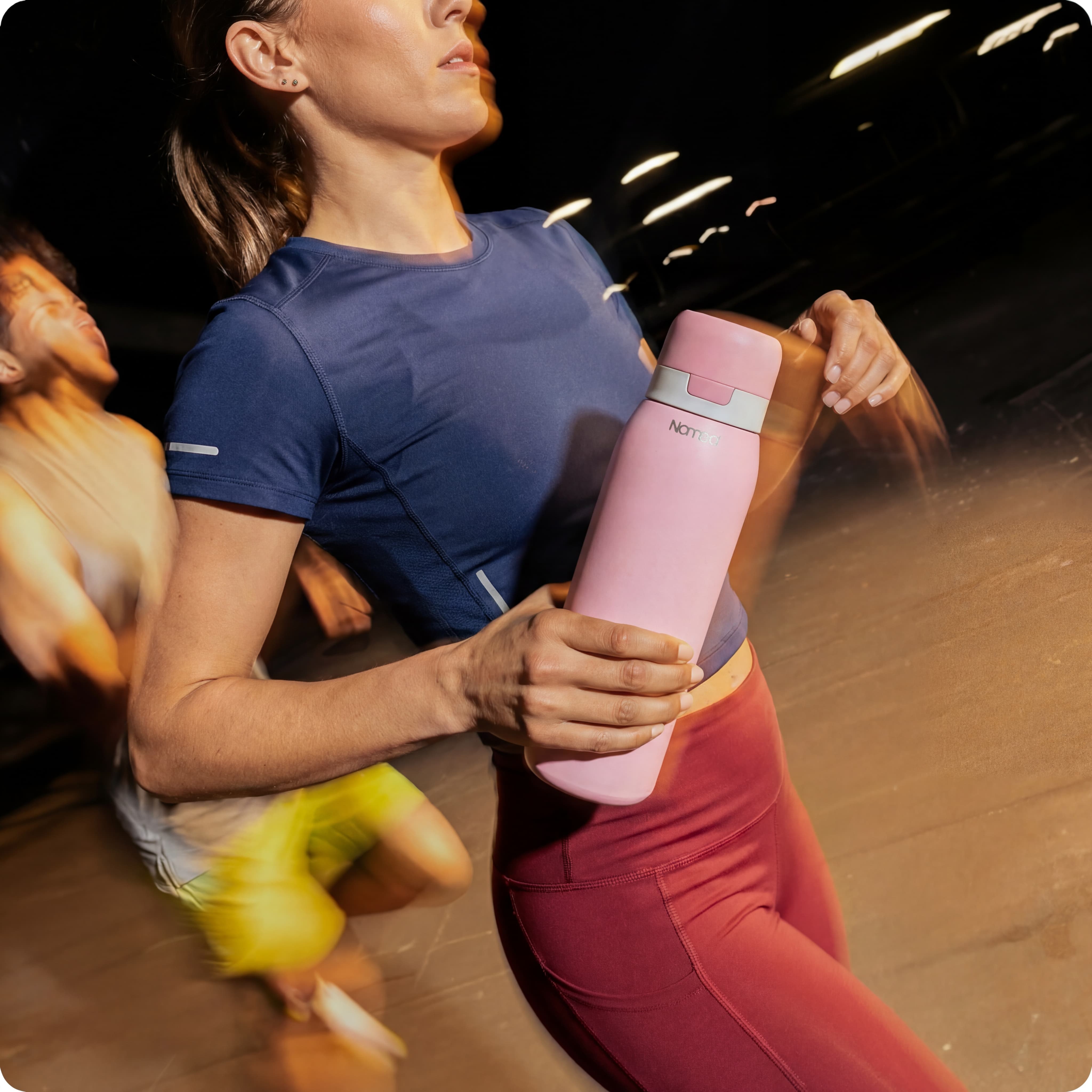 Person holding a pink NOMAD water bottle with blurred background