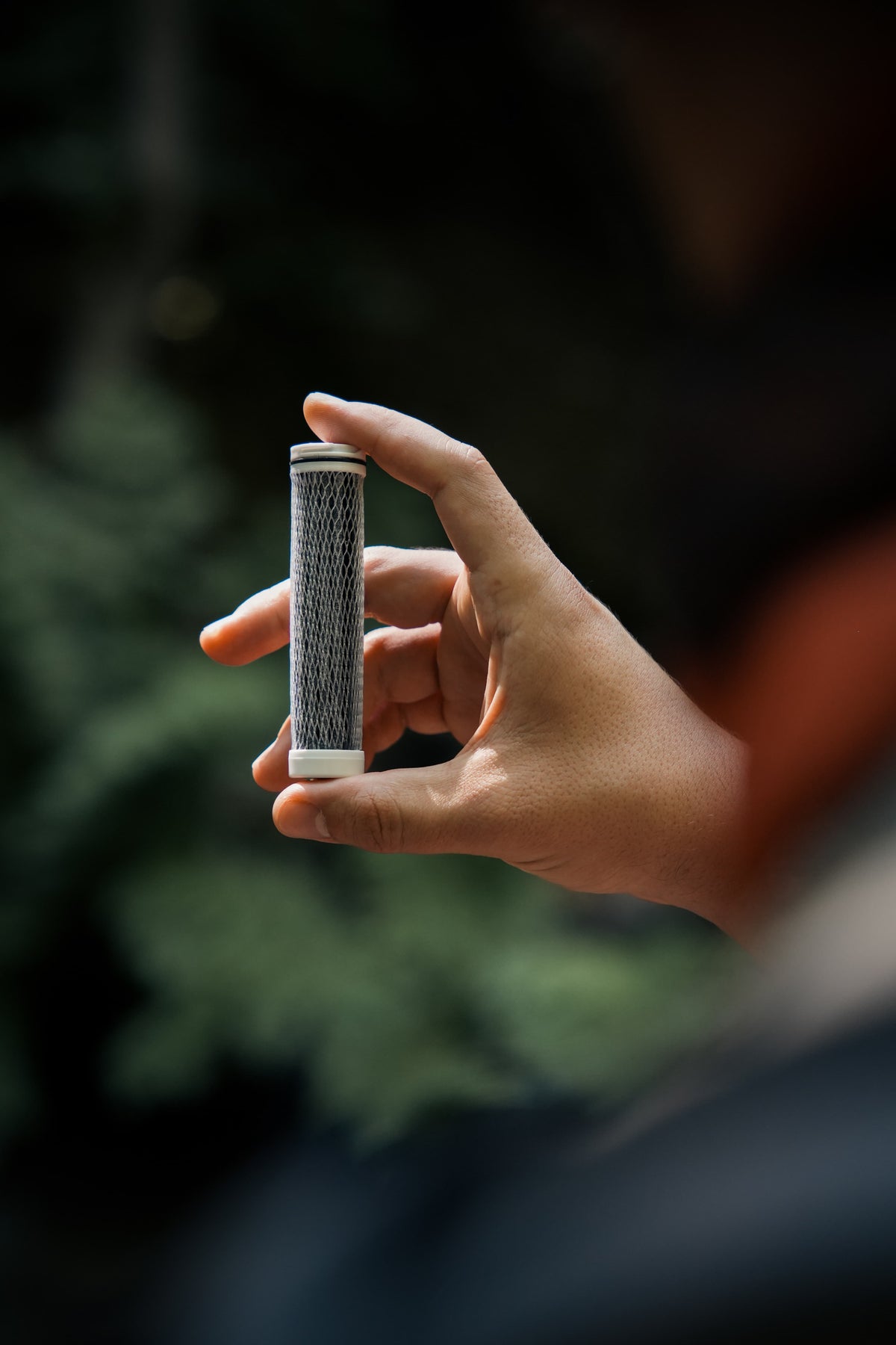 Close up of the AtomX replacement filter cartridge held outdoors for the NOMAD SafeSip water purifier bottle.