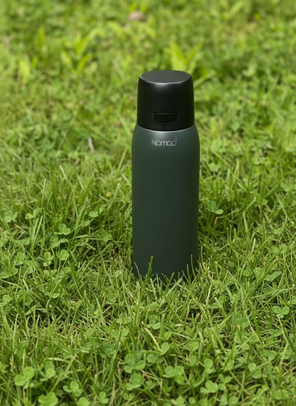 Dark green Filtered Bottle by Nomad placed on grass