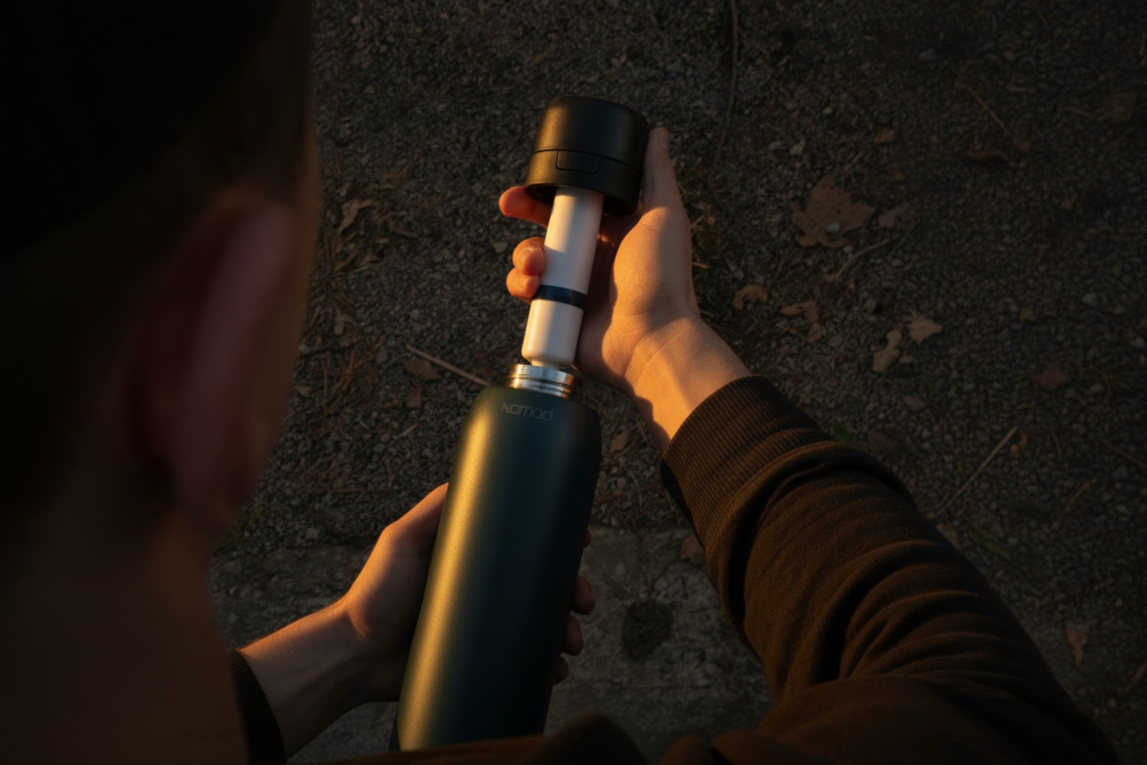 Person opening a green forest NOMAD filtered water bottle to show the removable internal filter cartridge