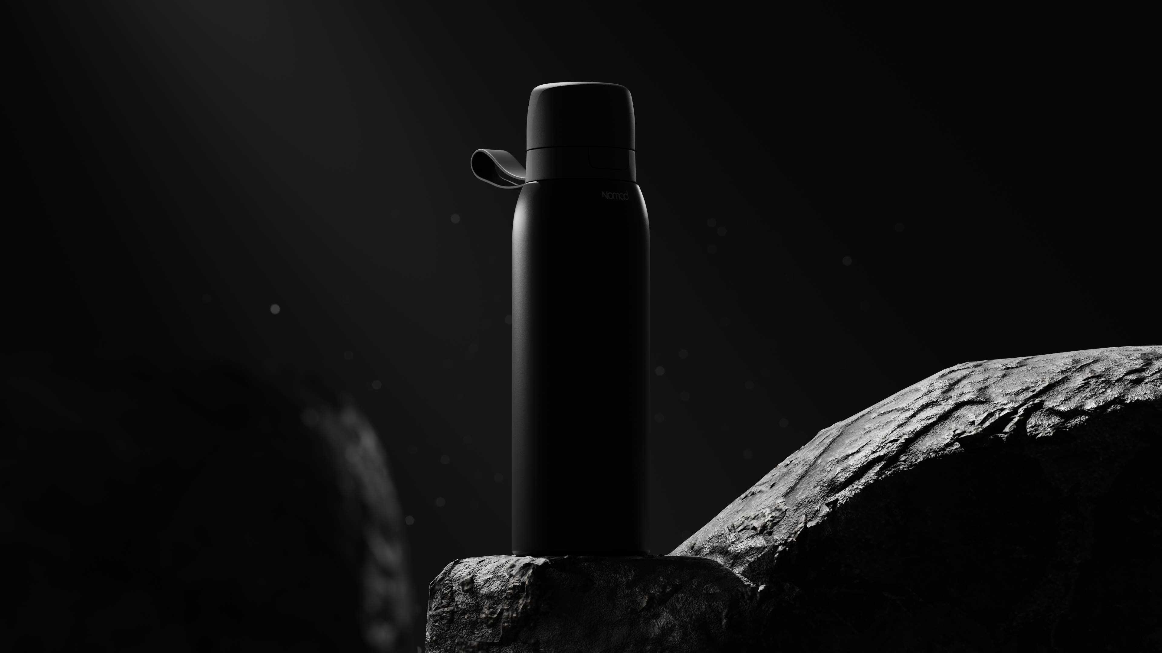 NOMAD Filtered Bottle Safesip is equipped with an advanced water purification system. Black water bottle on a rock with a dark background