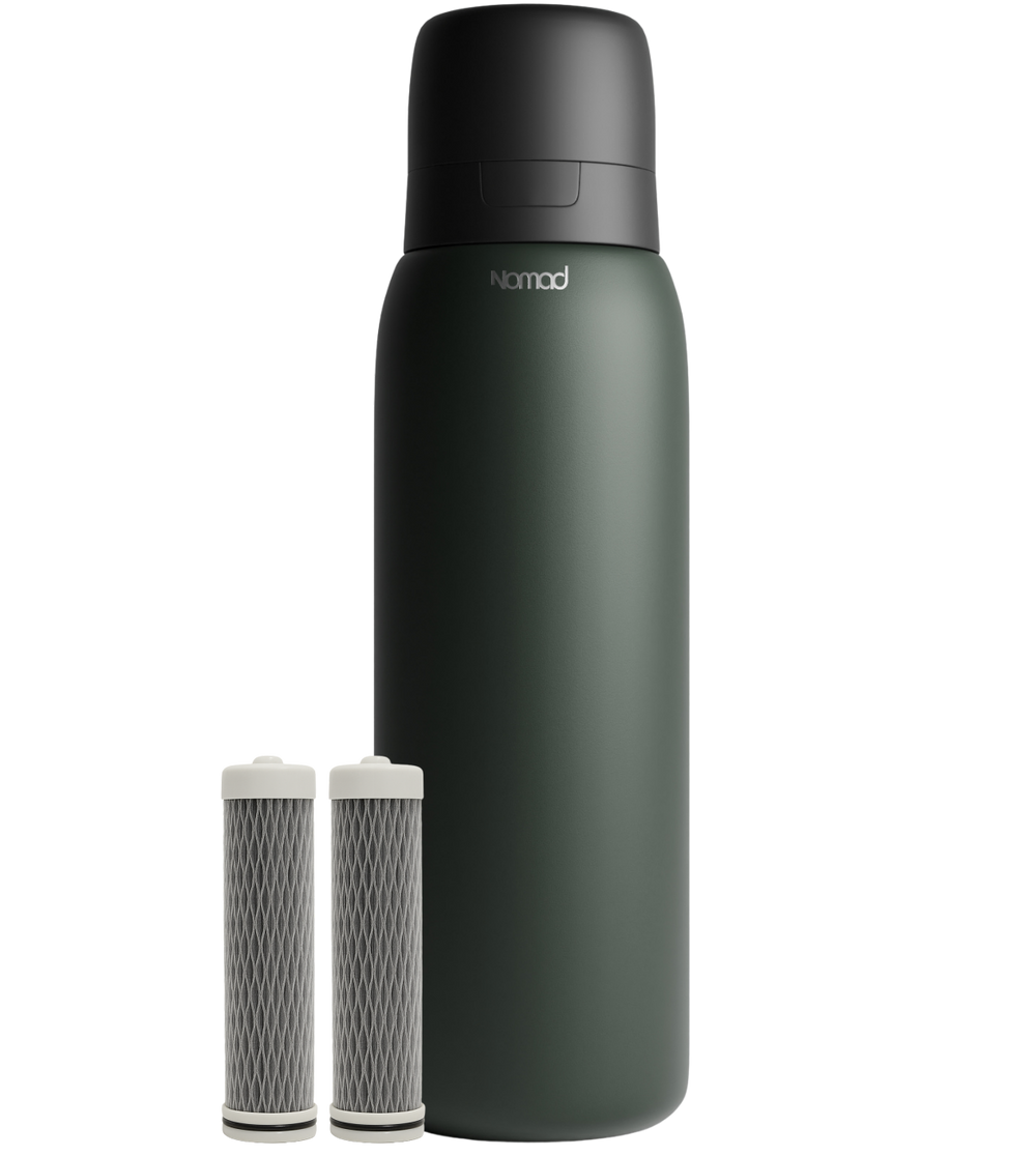 A matte dark green SafeSip insulated bottle with a black cap stands next to two cylindrical filter cartridges with white ends on a clean white background. The brand name 'NOMAD' is printed in white on the bottle.