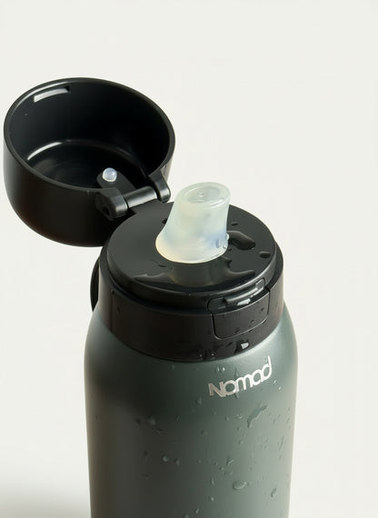 Black NOMAD filtered water bottle with a black cap on a wooden surface