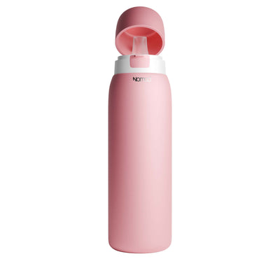 A matte pink SafeSip water bottle with a matching pink flip-up lid and a white collar, featuring the brand name 'NOMAD' printed in black near the top, set against a plain white background. 