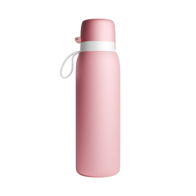 A matte pink NOMAD SafeSip Purifier water bottle with a matching pink cap, a white band around the neck, and a white carrying loop, shown on a plain white background. 
