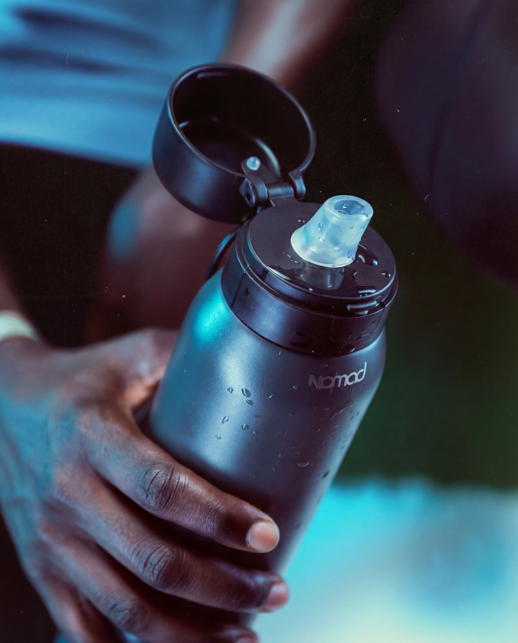 Person holding a green forest water purifier SafeSip bottle with 'NOMAD' branding.