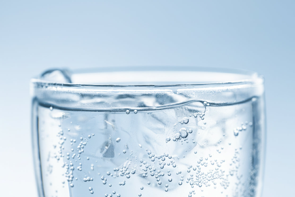 Close-up of a glass with a dark liquid and bubbles on a white and blue background